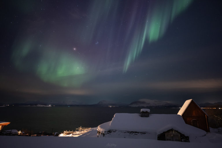 Ein mittelalterliches Langhaus und eine Stabkirche unter dem Nordlicht bei Trondenes nahe Harstad © Arne Widding